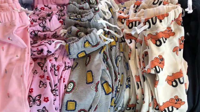 A collection of colorful patterned children's pajama pants hanging on display in a store.