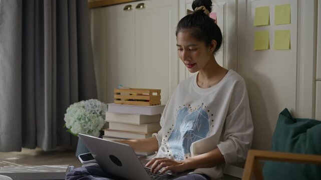 Asian woman working from home using smartphone AI assistant and laptop computer.voice message,voice command,AI agent interaction,remote workflow,communication,business and technology concept