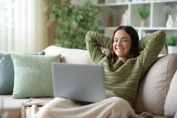 Plakat Happy young woman watching movie on laptop in winter