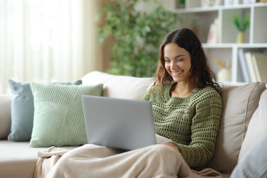 Happy young woman using laptop in winter at home