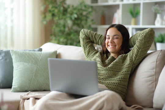 Happy young woman watching movie on laptop in winter
