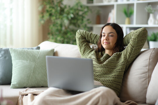 Relaxed young woman watching media on laptop in winter at home