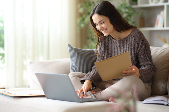 Happy young telecommuter working online holding folder at home