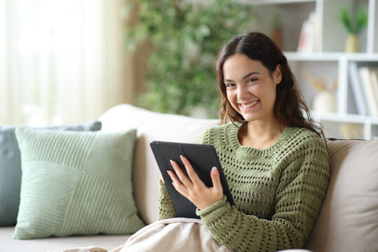 Happy young woman holding tablet and looking at you in winter