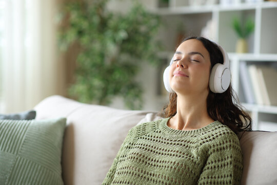 Young woman wearing headphones is relaxing at home