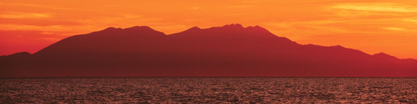 Seascape with mountains at sunset. Rockies in the evening. View of Mount Olympus on the horizon. Beautiful nature of Greece