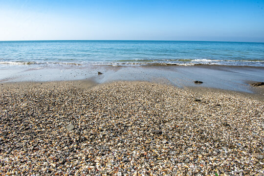 View of Saint Martins Island beach with pebbles and shells along the shoreline under a clear blue sky in Cox's Bazar District, Chittagong Division, Bangladesh.