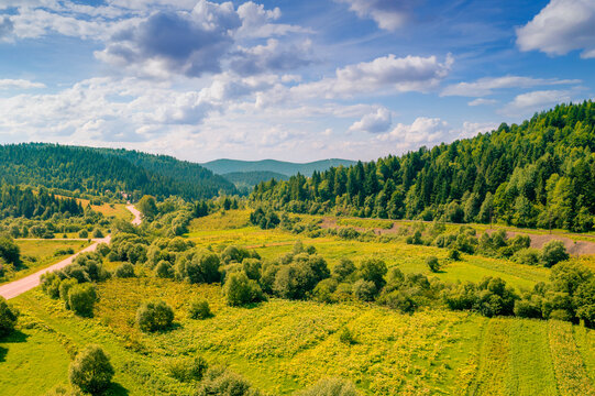 Aerial view of the countryside, country road and cultivated fields on the hills on a sunny spring day