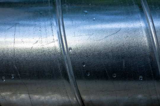 Close-up of a galvanized steel ventilation pipe with condensation water drops