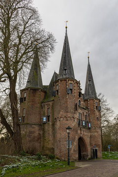 View of the historic Koornmarktspoort gatehouse with its distinctive brick towers and pointed roofs, set against a cloudy sky in Kampen, Overijssel, Netherlands.