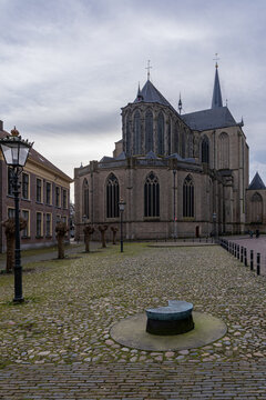 View of the historic Bovenkerk church with its gothic brick architecture and tall spire overlooking a cobblestone square in Kampen, Overijssel, Netherlands.