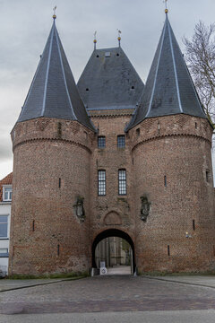 View of the historic Koornmarktspoort city gate in Kampen, featuring twin towers, brick facade, and arched entrance under an overcast sky in Kampen, Overijssel, Netherlands.