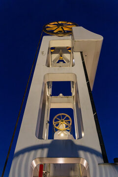 View of the Stadsbrug Kampen bridge mechanism featuring white structural supports and gold-colored pulleys against a clear night sky in Kampen, Overijssel, Netherlands.