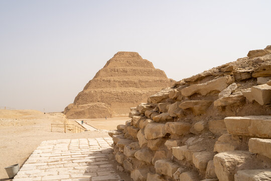View of the Step Pyramid of Djoser with ancient stone masonry in the foreground under a clear sky in Badrshein, Giza Governorate, Egypt.