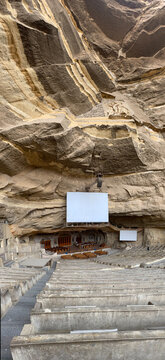 View of the Cave Church of Saint Simon, a massive amphitheater carved into the Mokattam mountain rock face with wooden pews and a projection screen in Cairo, Cairo Governorate, Egypt.