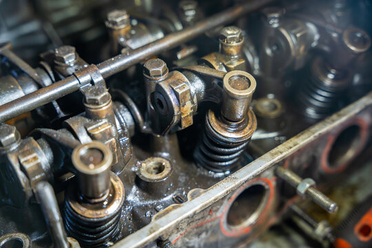 Disassembled car engine with exposed valve train and cylinder head. Internal engine components represent automotive repair, diagnostics and maintenance
