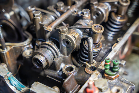 Disassembled car engine with exposed valve train and cylinder head. Internal engine components represent automotive repair, diagnostics and maintenance