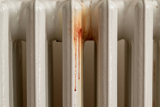 Close-up of old radiators with rust stains on a white surface  