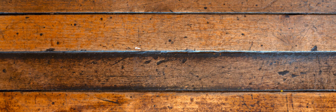 Panorama of unpainted varnished old scratched wooden floorboards for use as a background texture