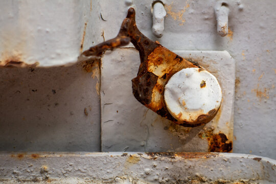 Rusty old metal hinge detail on industrial painted steel machinery surface