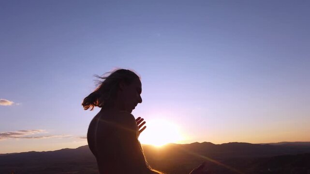  Slow motion of silhouette of shirtless man with long hair dancing against the sunset sky 