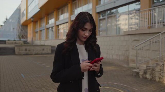 Focused young woman browsing smartphone in urban business setting