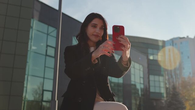 Confident young woman recording herself with smartphone in city