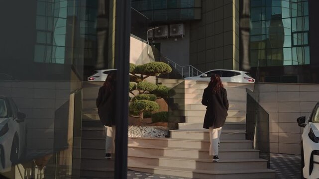 Woman in black coat climbing outdoor steps in sunny urban setting