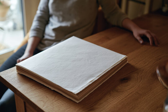 A closed sketchbook rests on a polished wooden table, symbolizing a moment of pause in a creative journey, awaiting the next burst of inspiration for artistic expression.