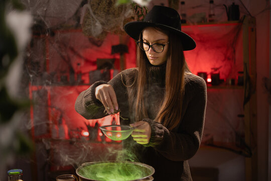 A realistic witch brewing a potion in a cauldron. She recites a spell and tosses dried herbs into the cauldron. A blend of everyday life with traditional witchcraft, magic, and a mystical atmosphere