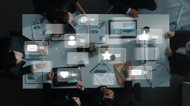 Overhead view of a diverse business team engaged in a meeting, analyzing data while interactive digital icons enhance the workspace atmosphere and productivity. Raster