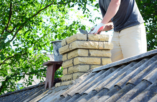Brick chimney repair renovation by builder on house rooftop