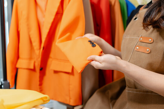Professional fashion designer inspecting garment details, comparing fabric colors and checking clothing quality in a modern fashion studio. Creative apparel development and textile craftsmanship.