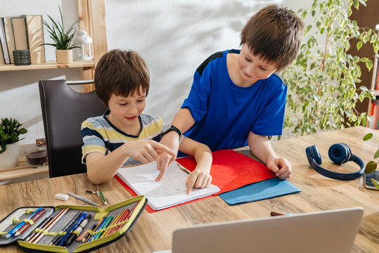 Brothers studying homework together, receiving help at home
