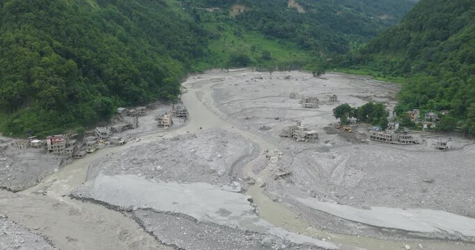 Betrawati Nepal, aerial shot of the vast devastation across the Trishuli River basin, of ruined residential buildings nestled between forest hills and completely engulfed by heavy mud slit