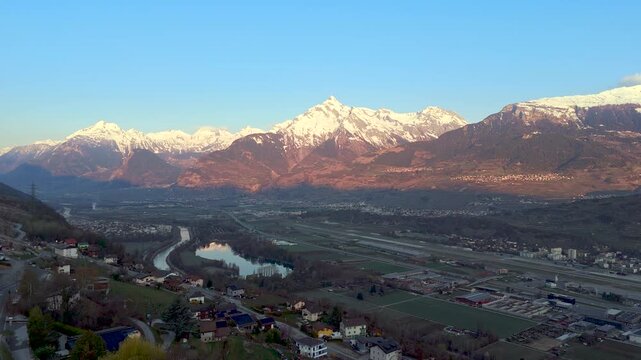 Sion in Rhone Valley at sunrise and snow-capped peaks of Swiss Alps. Drone riser