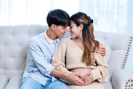 Heavily pregnant asian woman in her third trimester is enjoying her romance time at home with her supporting husband in relax and calm for maternity and happy family and motherhood parenting