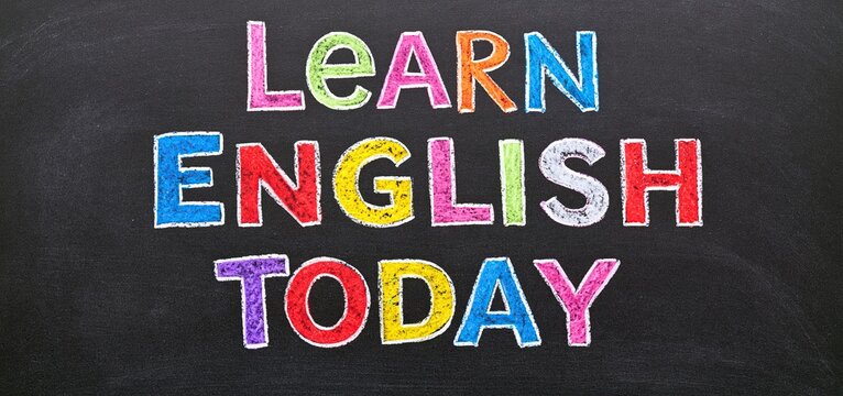 Colorful chalk lettering on a blackboard displaying the phrase encouraging English learning.
