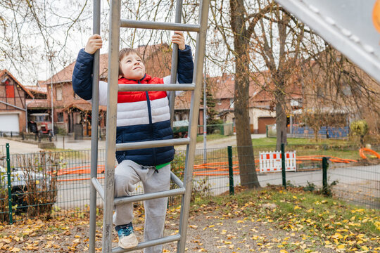 Young boy climbing playground ladder reaching for success