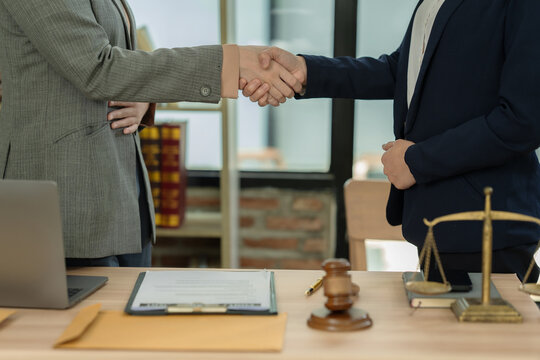 Business partners handshaking after successful contract signing and legal agreement consultation at law firm.