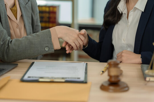 Business partners handshaking after successful contract signing and legal agreement consultation at law firm.
