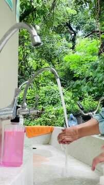 Children washing hands with liquid soap at an outdoor sink station for hygiene, personal care, and disease prevention in a school or park setting.
