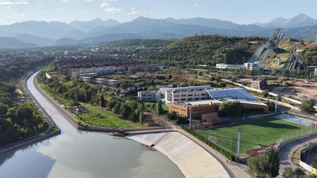 Top-down aerial view of river promenade park and dam infrastructure at early morning