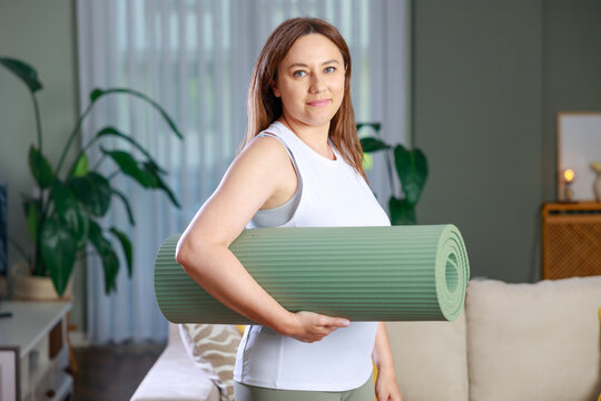 Woman carrying yoga mat at home