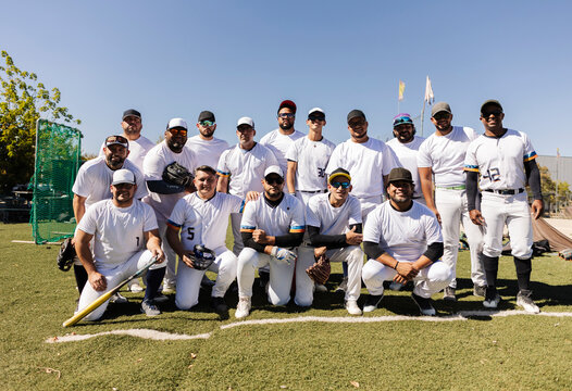 Diverse baseball team posing on green playing field