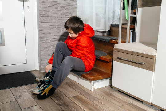 Boy sitting on stairs putting on sneakers getting ready