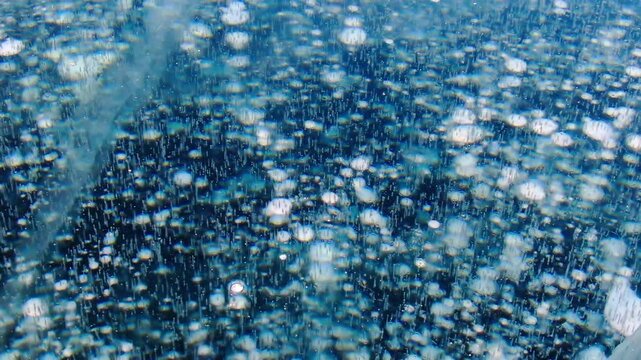 Methane bubbles trapped under thick blue lake ice background. Natural phenomenon gas frozen in cold winter water surface. Beautiful texture of arctic landscape, ecological climate change concept.