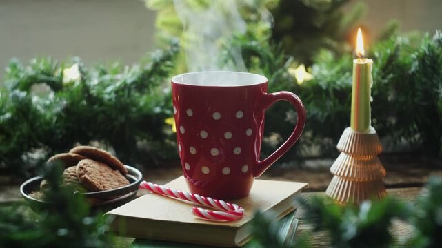 Pouring boiling water into a red polka dot cup. Drinking hot tea or coffee, Christmas decorations on background. Cozy winter season.