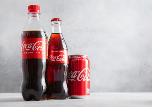 LONDON,UK - JULY 25,2025: Original Taste Coca Cola soft soda drink bottles and aluminium tin on light table background.
