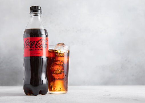 LONDON,UK - JULY 01,2025: Bottle of Zero Sugar Coca Cola soft soda drink with glass of ice cubes on light table background.